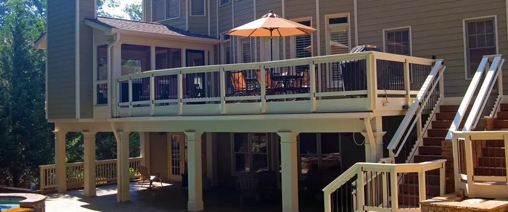 Elevated backyard deck with stairs, outdoor dining area and covered patio overlooking a swimming pool.