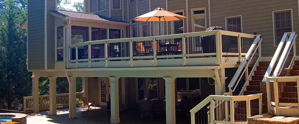 Elevated backyard deck with stairs, outdoor dining area and covered patio overlooking a swimming pool.