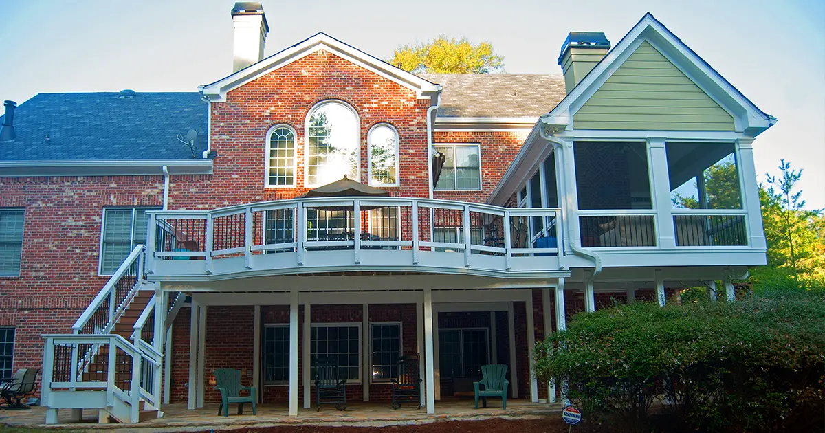 Elevated deck and screened porch addition with stairs, black railings and covered patio below.
