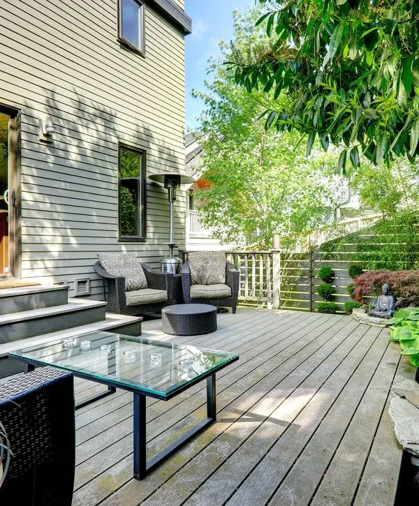 Modern backyard deck with outdoor lounge furniture, cable railing and garden landscaping.