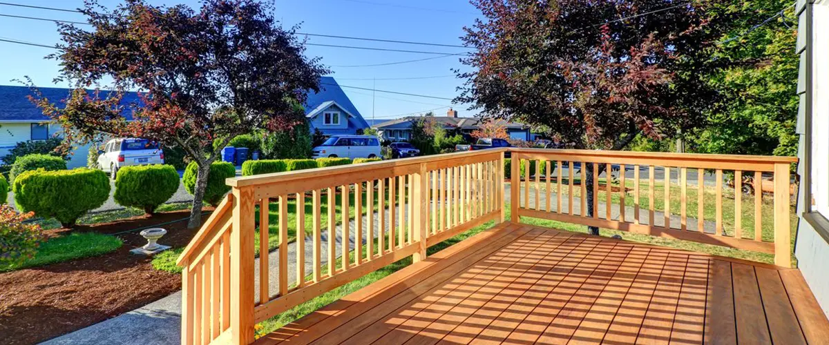New wood deck with natural railings and stairs overlooking a landscaped front yard.