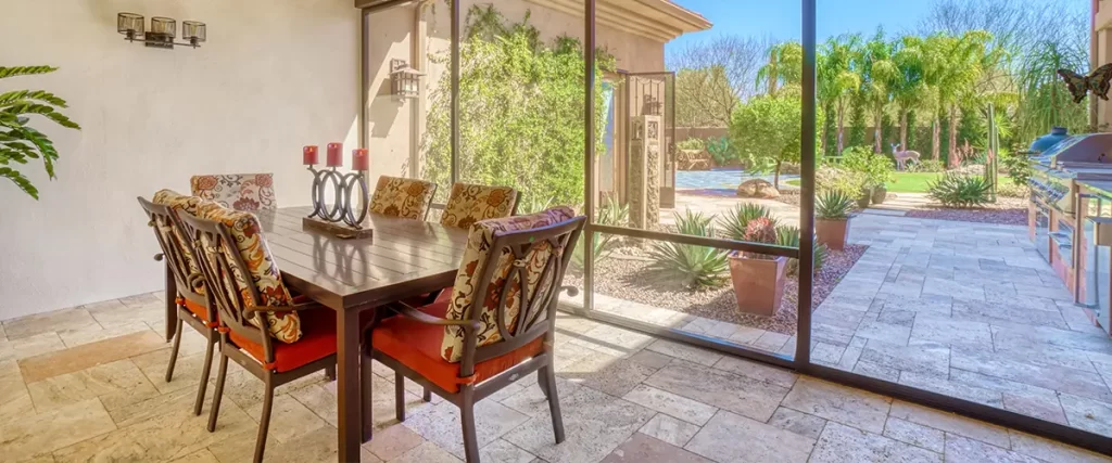 Screened patio enclosure with dining area, wood ceiling and views of a landscaped backyard.