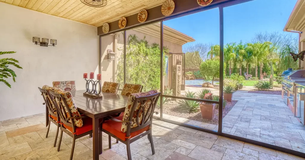 Screened patio enclosure with dining area, wood ceiling and views of a landscaped backyard.
