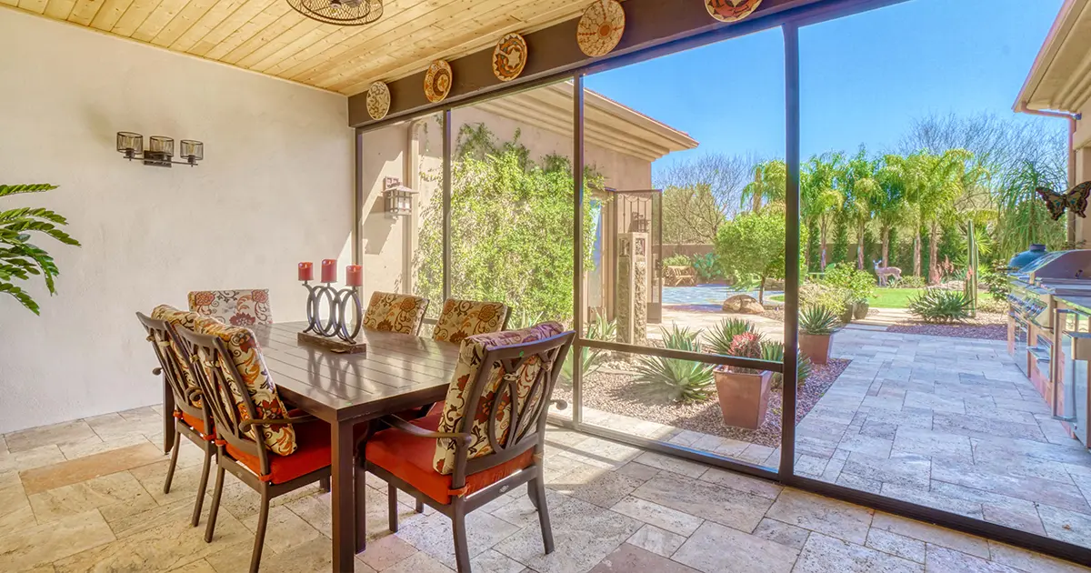 Screened patio enclosure with dining area, wood ceiling and views of a landscaped backyard.