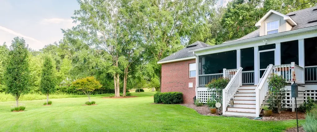 Screened porch addition on a brick home overlooking a spacious landscaped backyard.