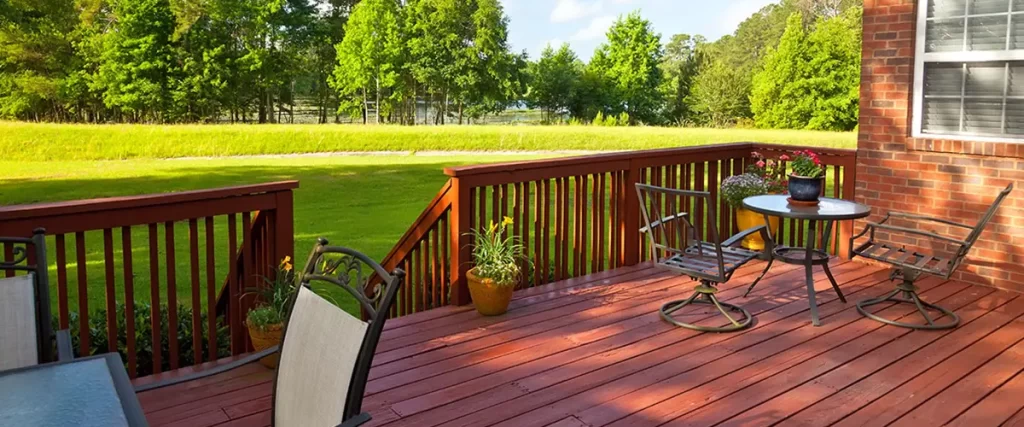 Wood deck with outdoor seating, red railings and views of a landscaped backyard.