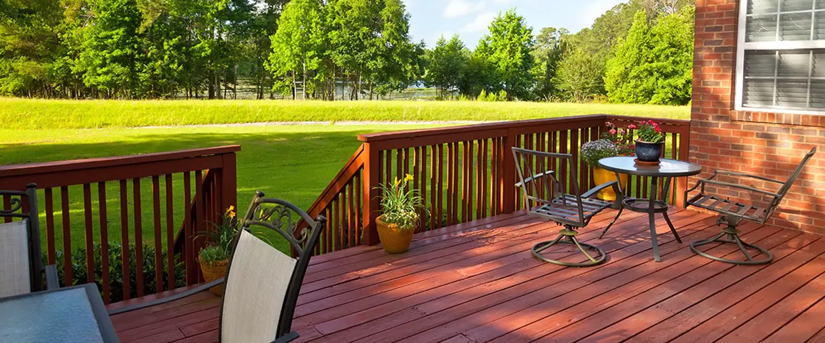 Wood deck with outdoor seating, red railings and views of a landscaped backyard.