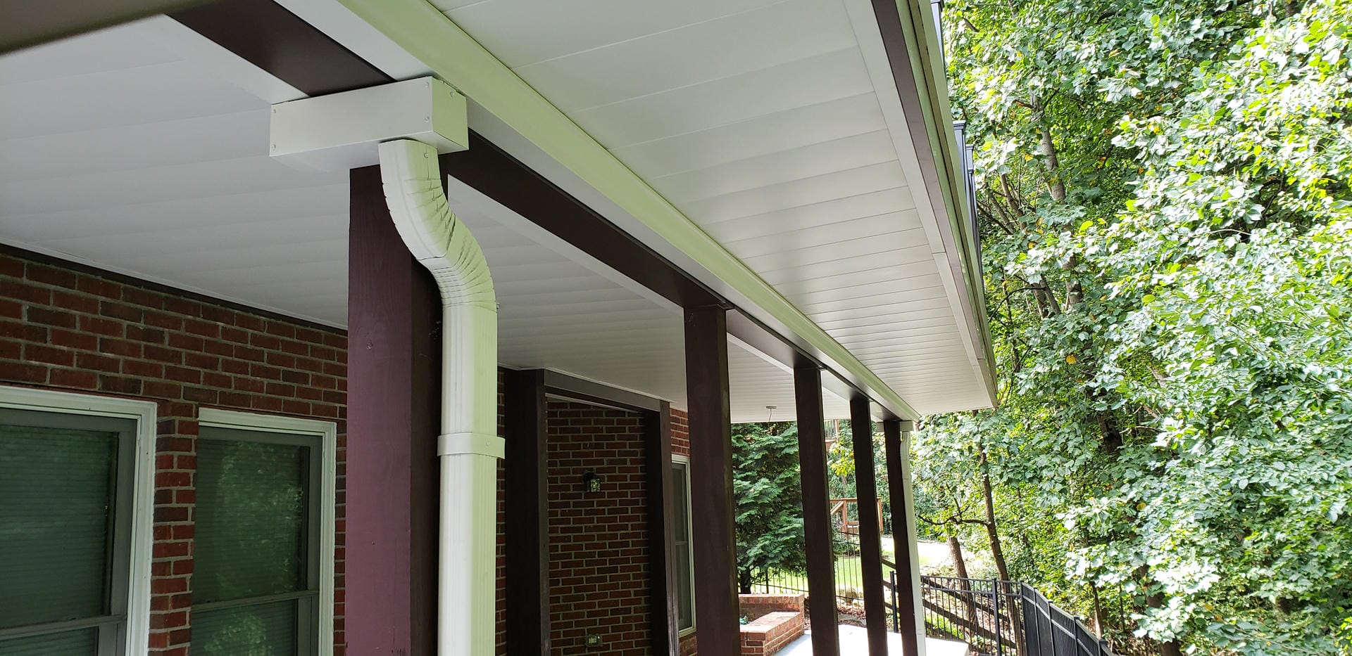 Close view of white aluminum under decking panels and the drainage downspout