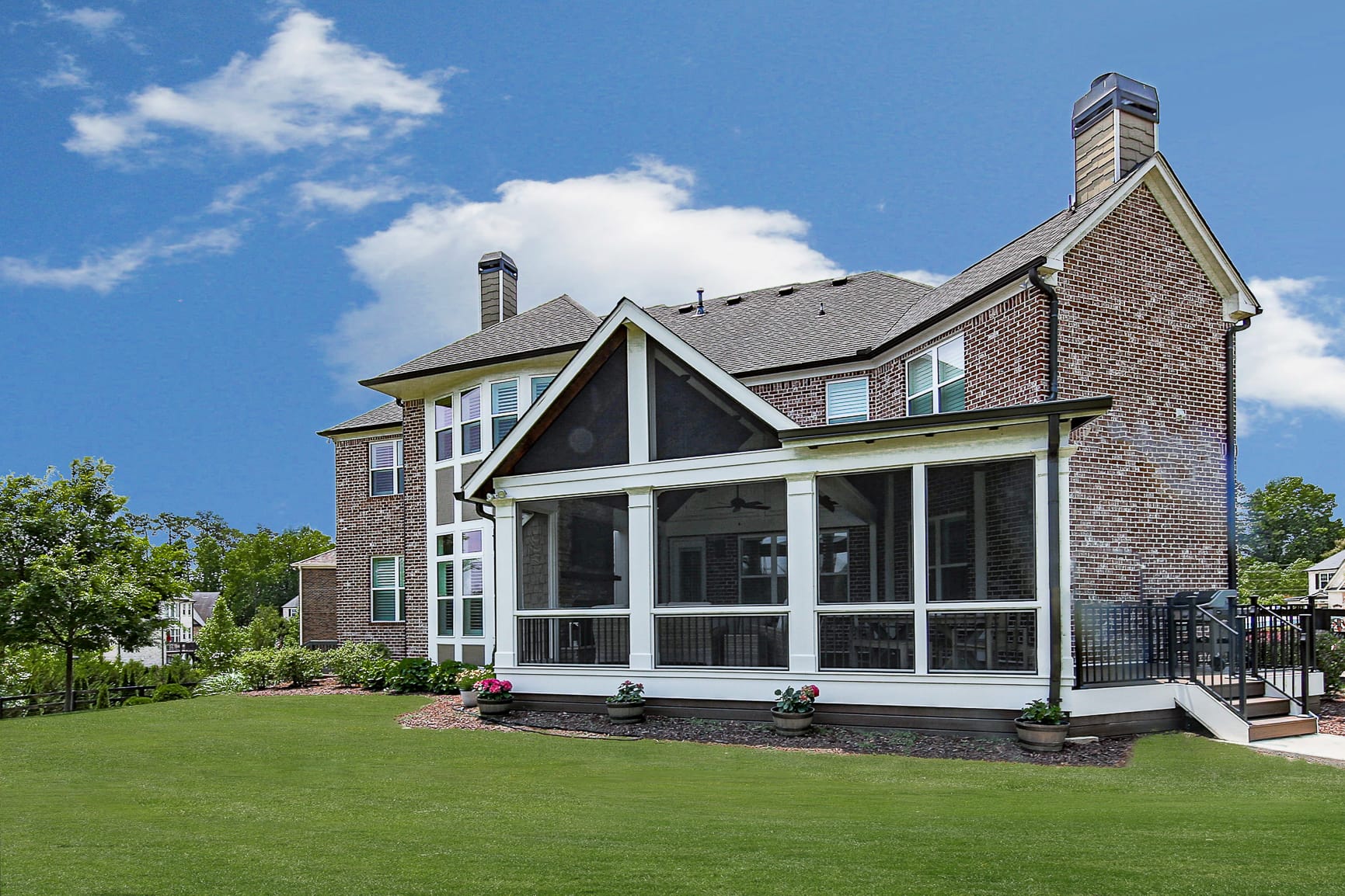 Screened porch on a brick home with a gable end and a shed roof running to the chimney