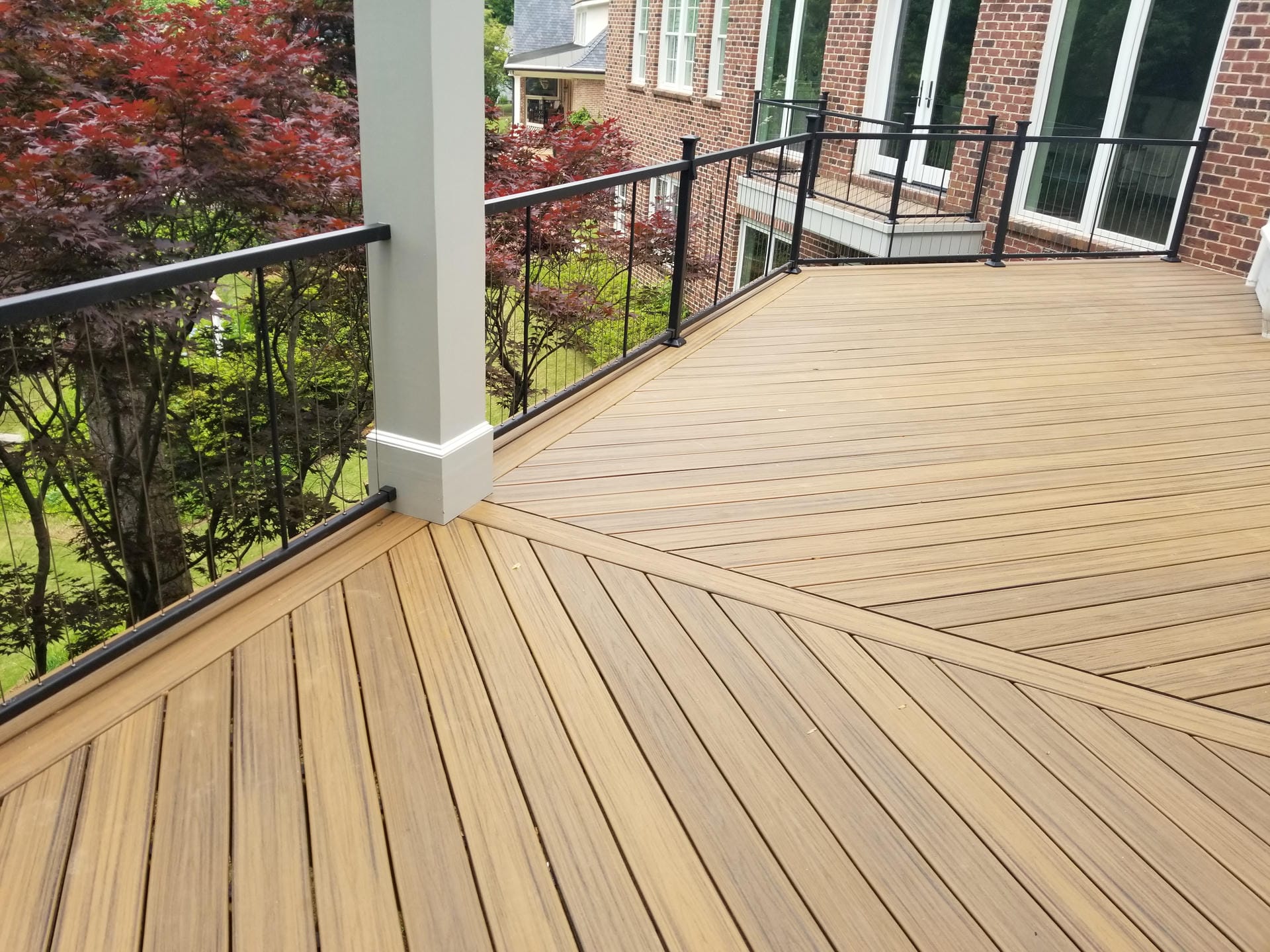 Honey toned composite decking laid in a diagonal pattern beside a white column