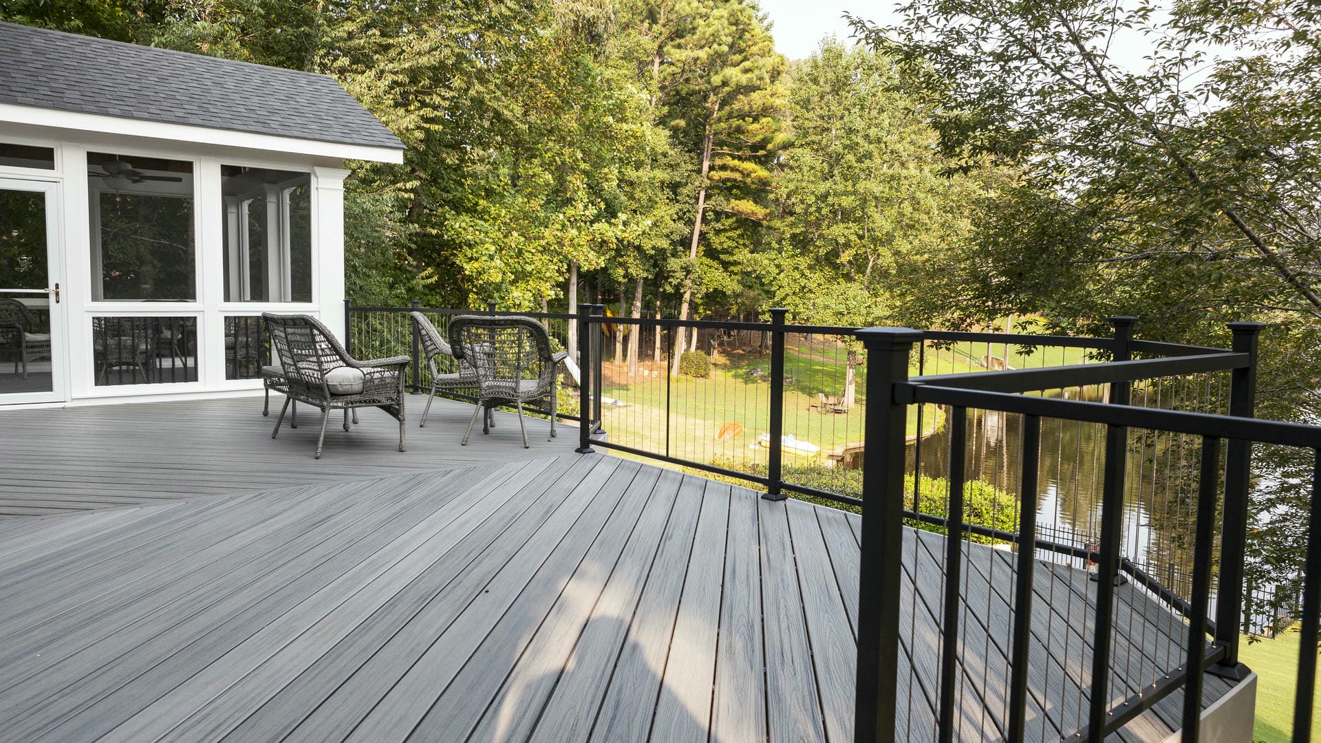 Grey composite deck with black metal railing looking out over woods and water