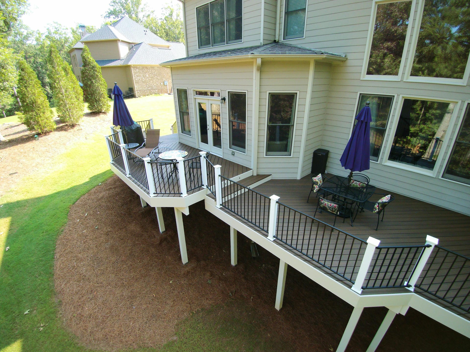 Wraparound deck railing with white posts, black balusters and lighted post caps