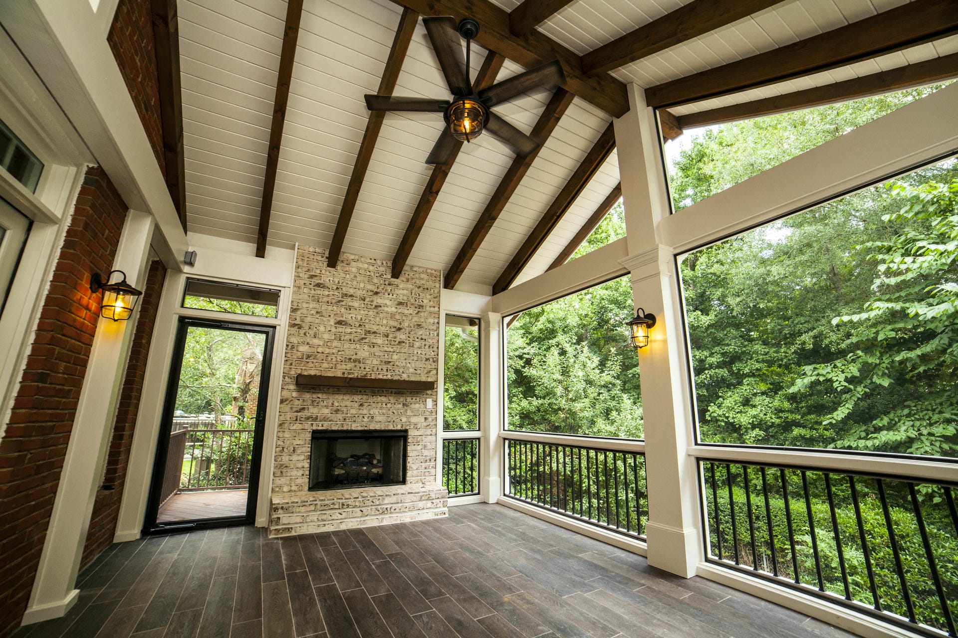 Exposed cedar rafters above a brick outdoor fireplace on a screened porch