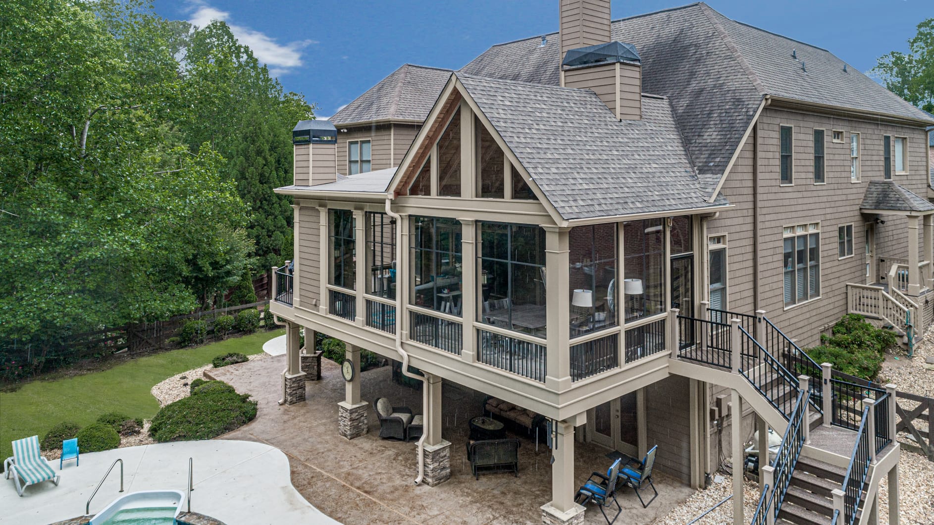 Aerial view of a steep gable porch roof over a screened porch on stone columns