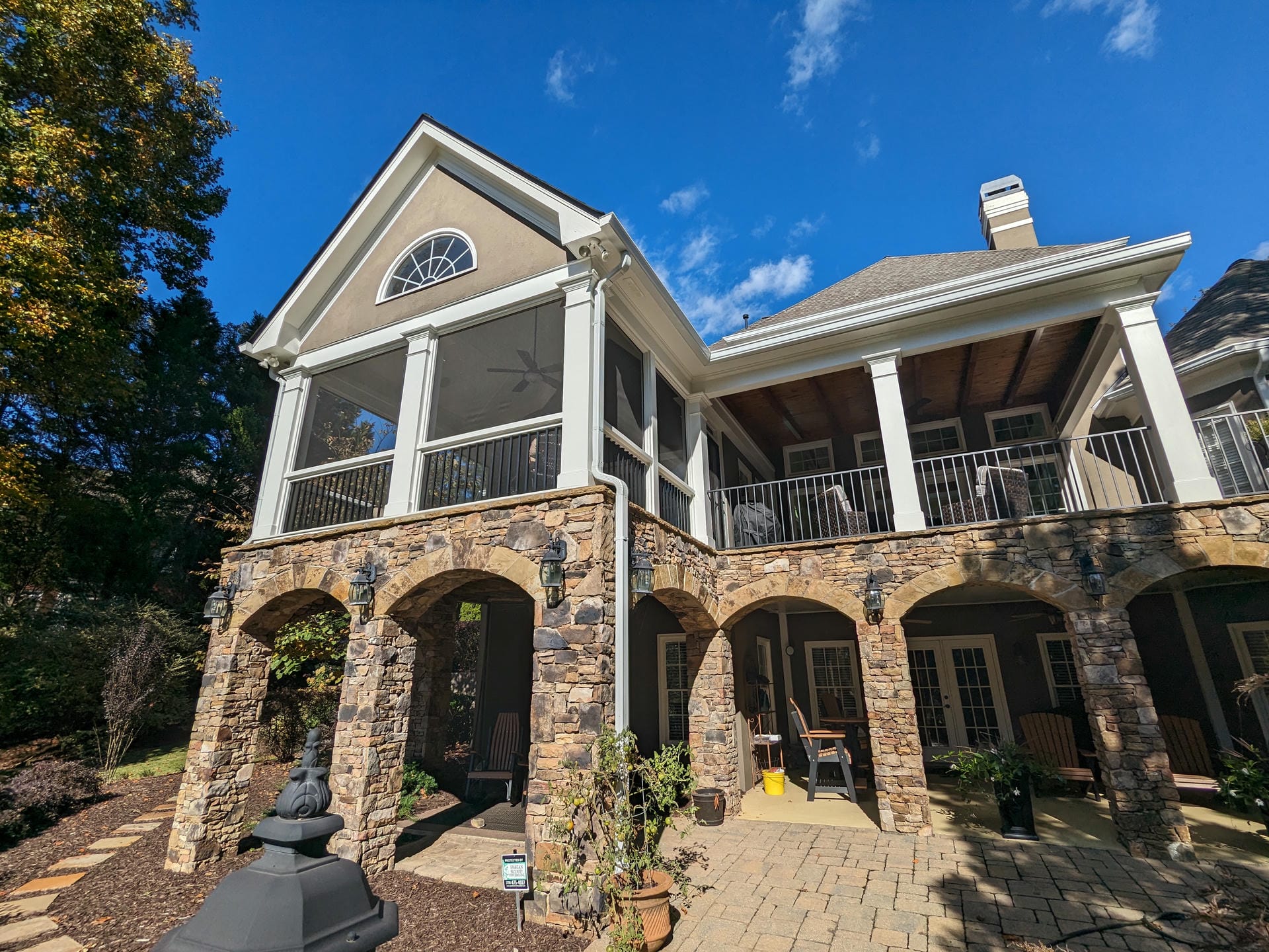Tall gable porch roof with an arched window in the gable above stone arches