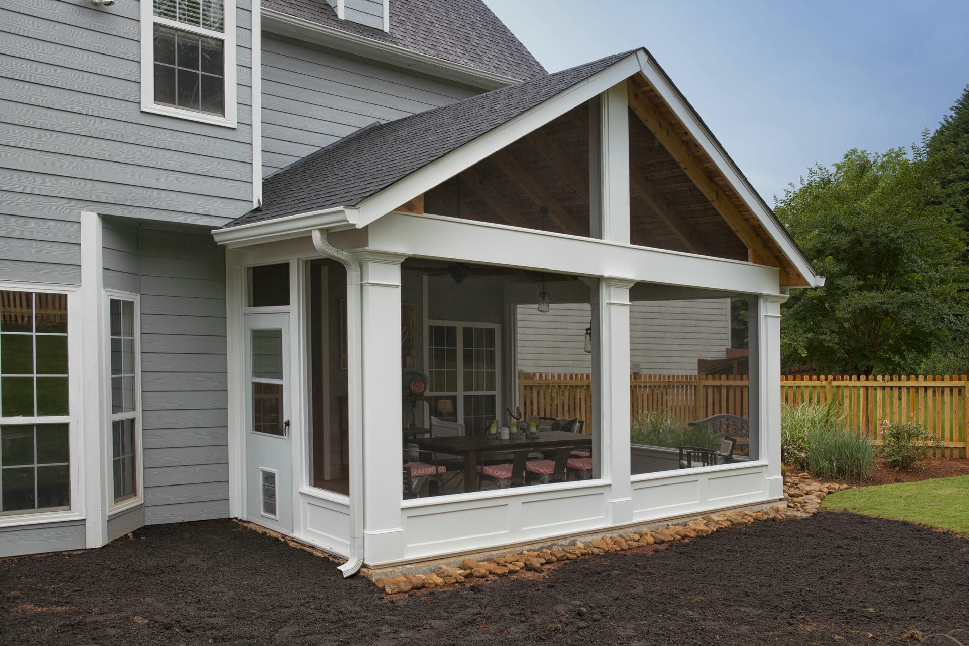 Screened porch with a gable roof and an open timber gable end on a gray siding home