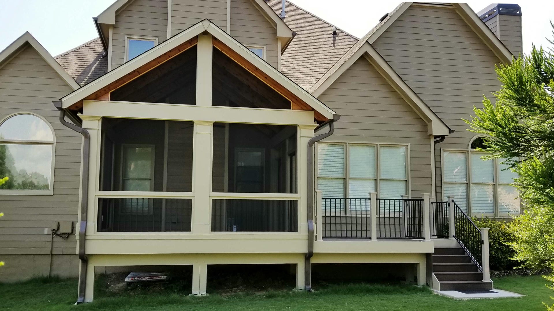 Screened porch with a gable roof and stained beam detail beside an open deck