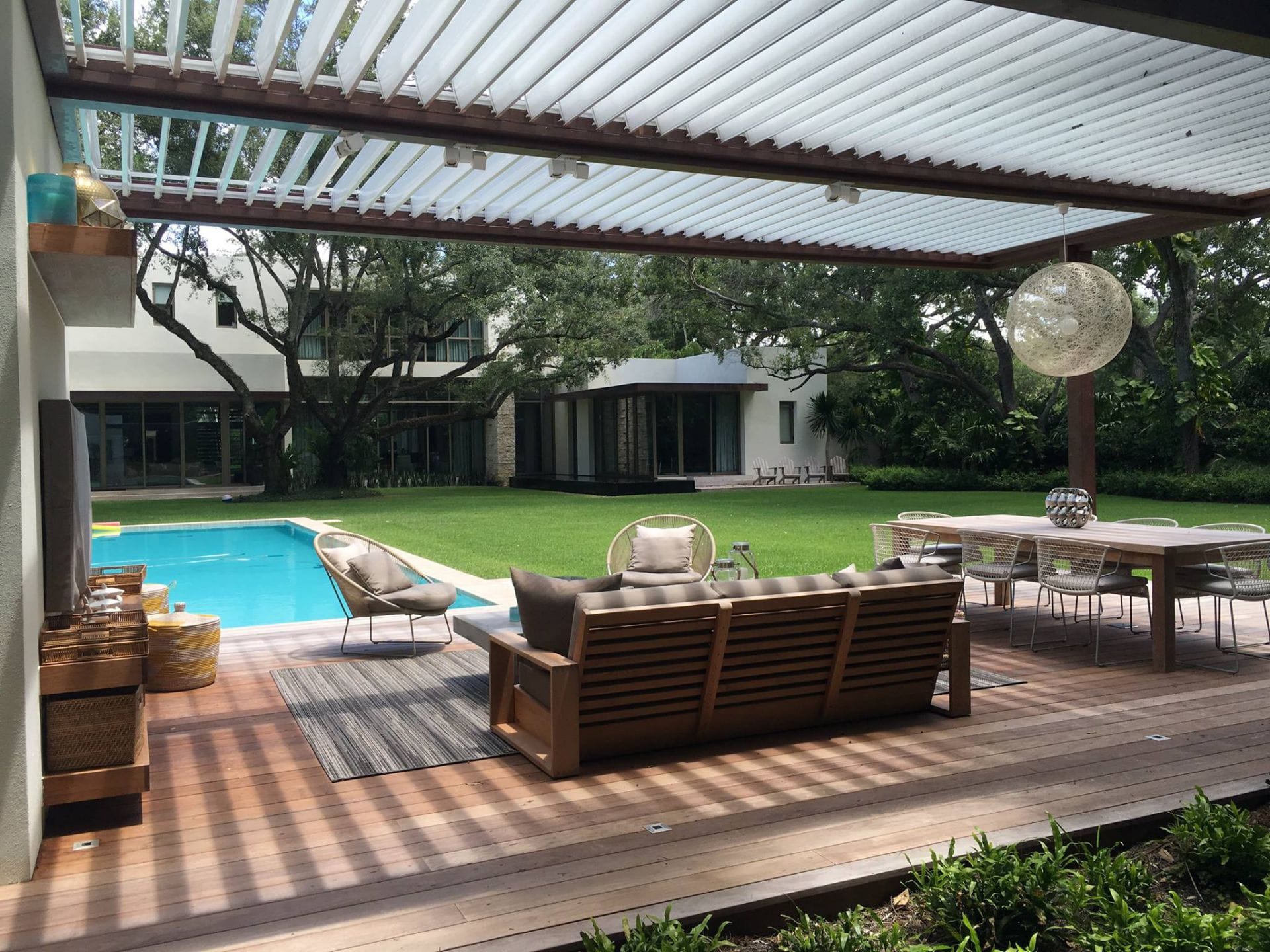 Equinox louvered roof with the louvers open over a deck seating area beside a pool