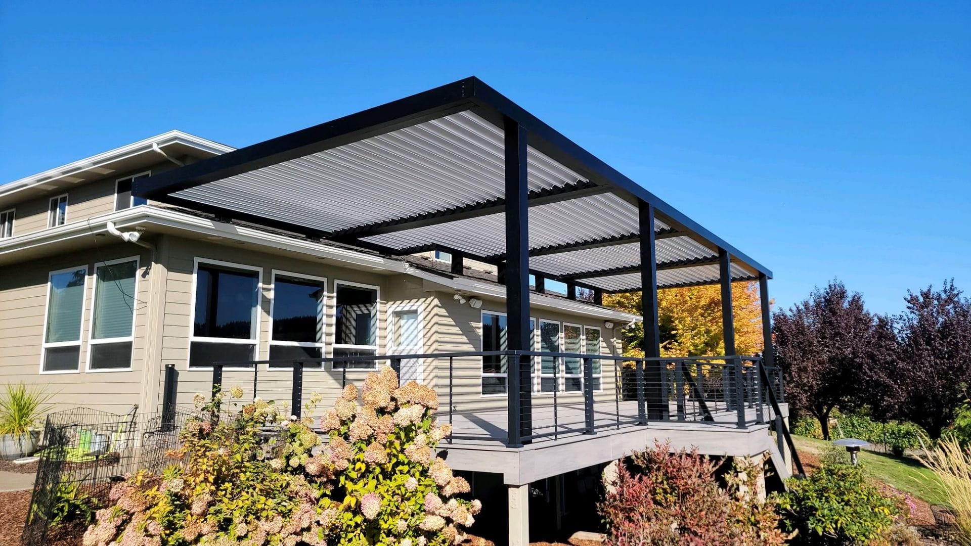 Dark aluminum louvered roof over an elevated deck with cable railing