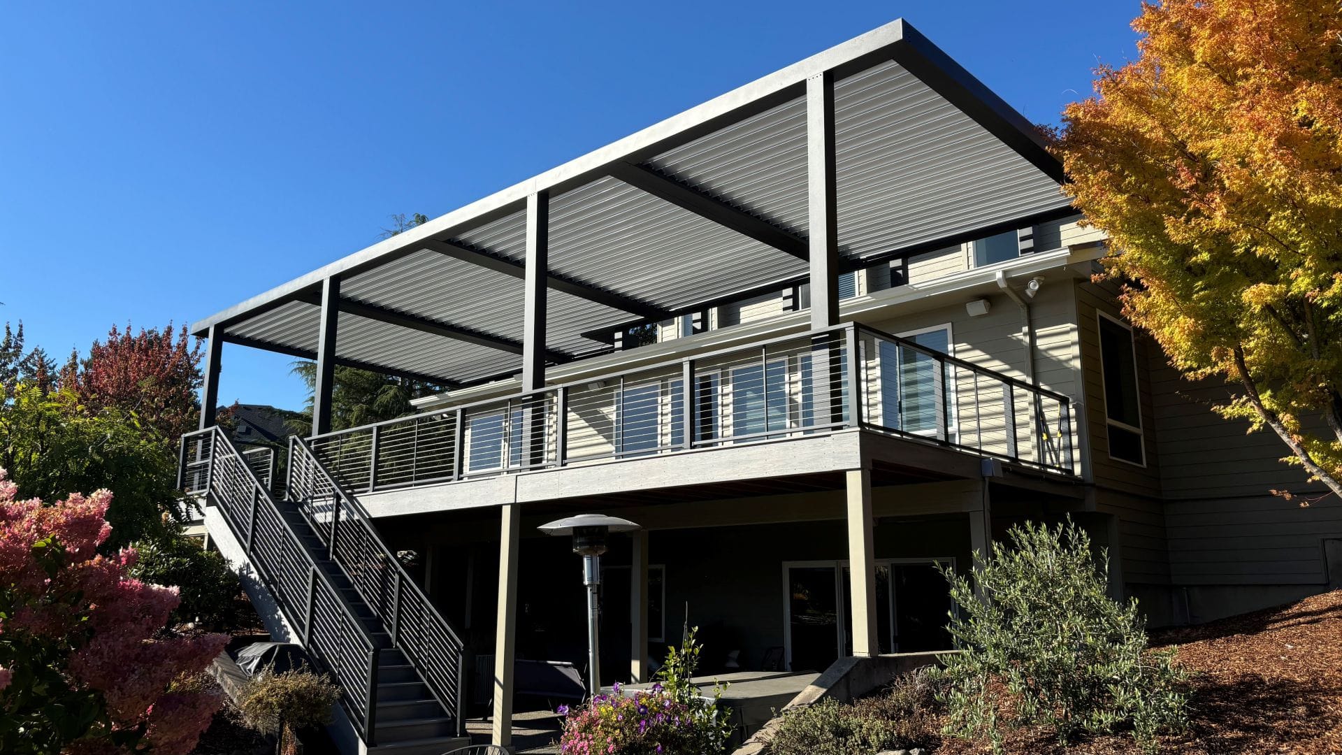 Side view of an aluminum louvered roof over an elevated deck in autumn