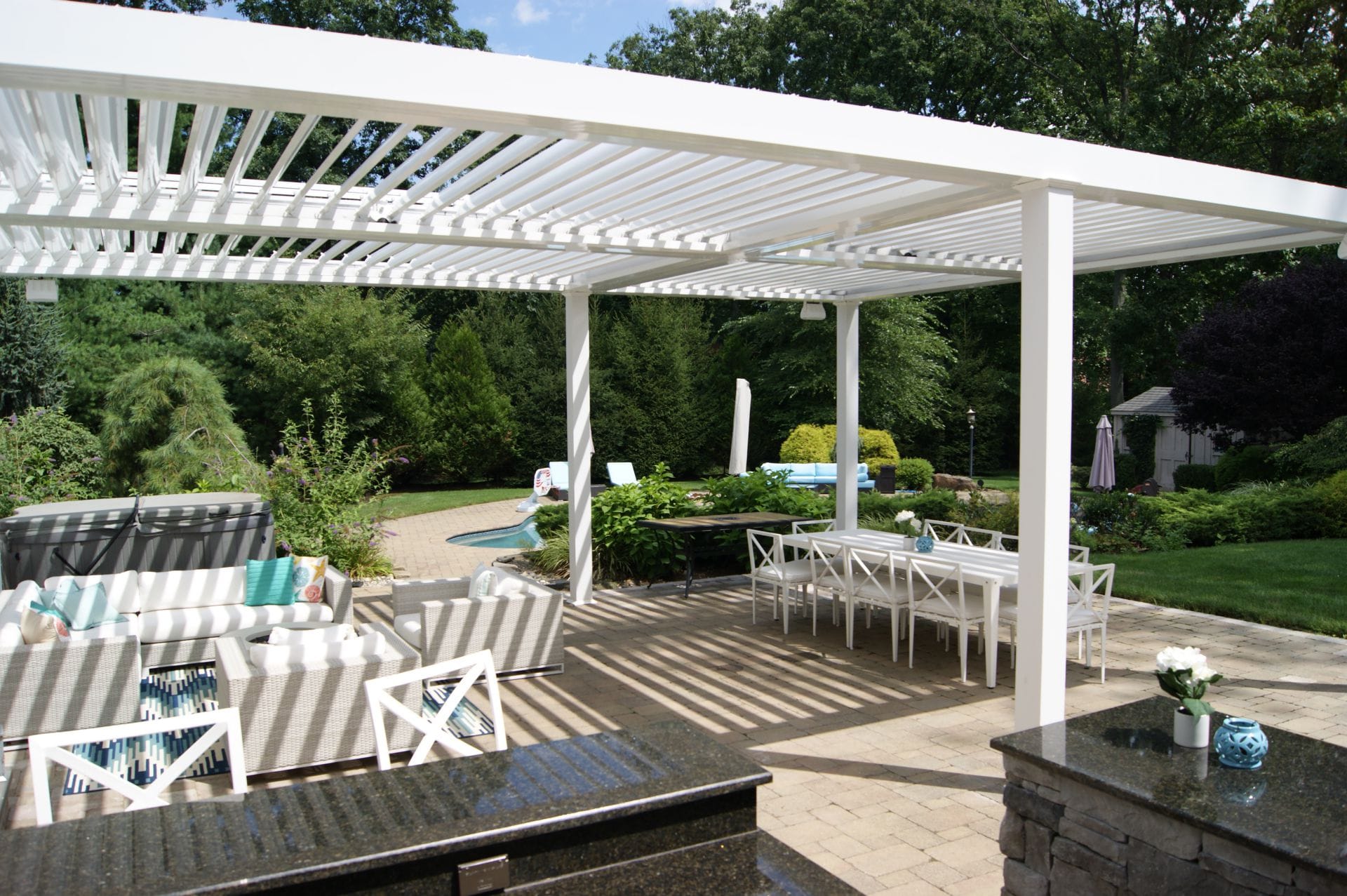 Large white louvered roof over a patio dining and lounge area
