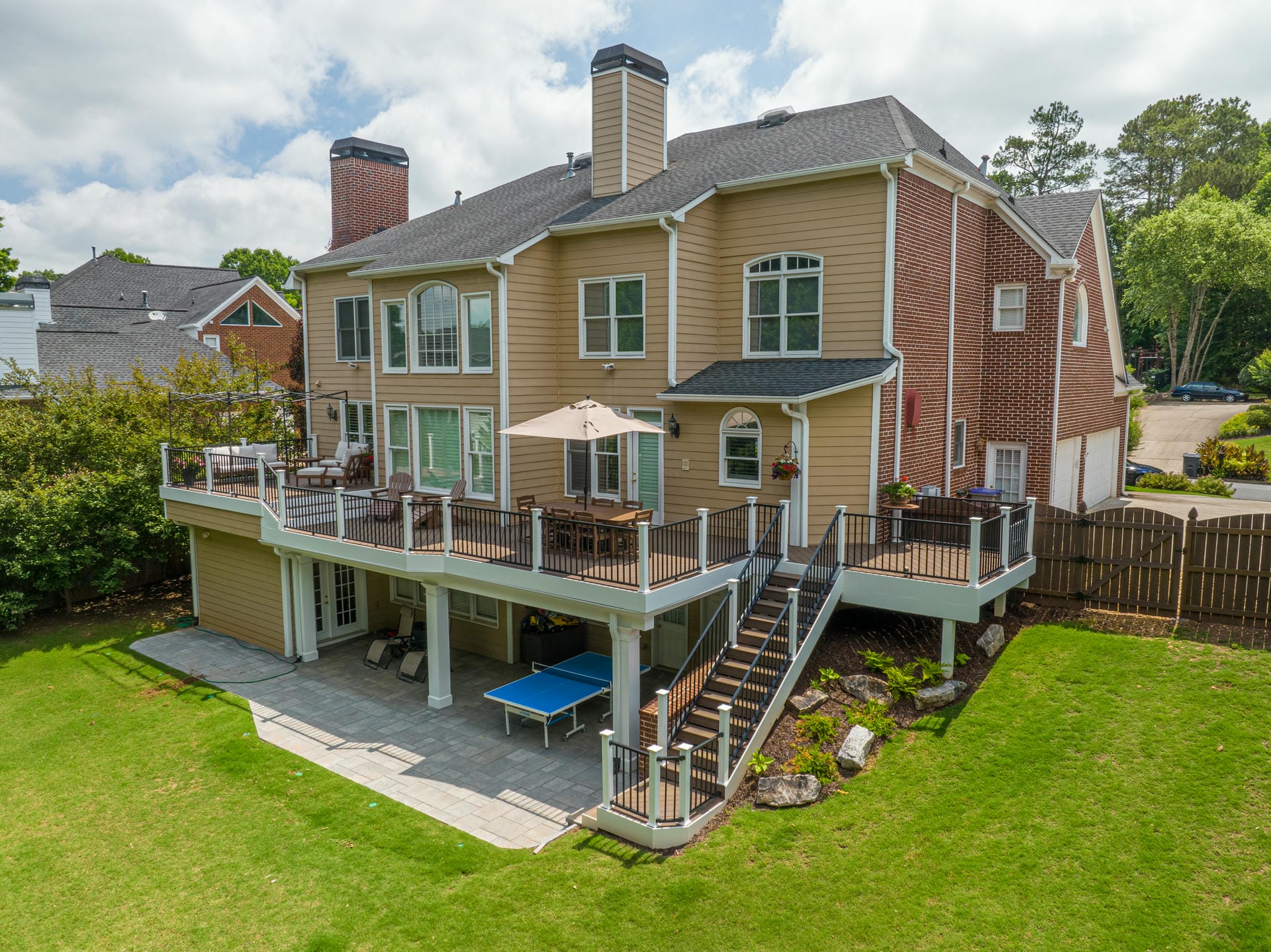 Two level composite deck with black metal railing above a paver patio at the back of a North Atlanta home
