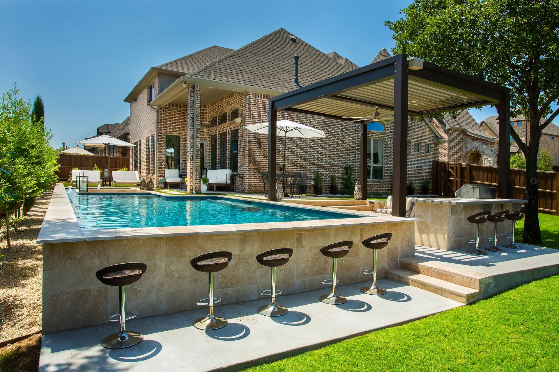 Bronze motorized pergola over a poolside bar with stools