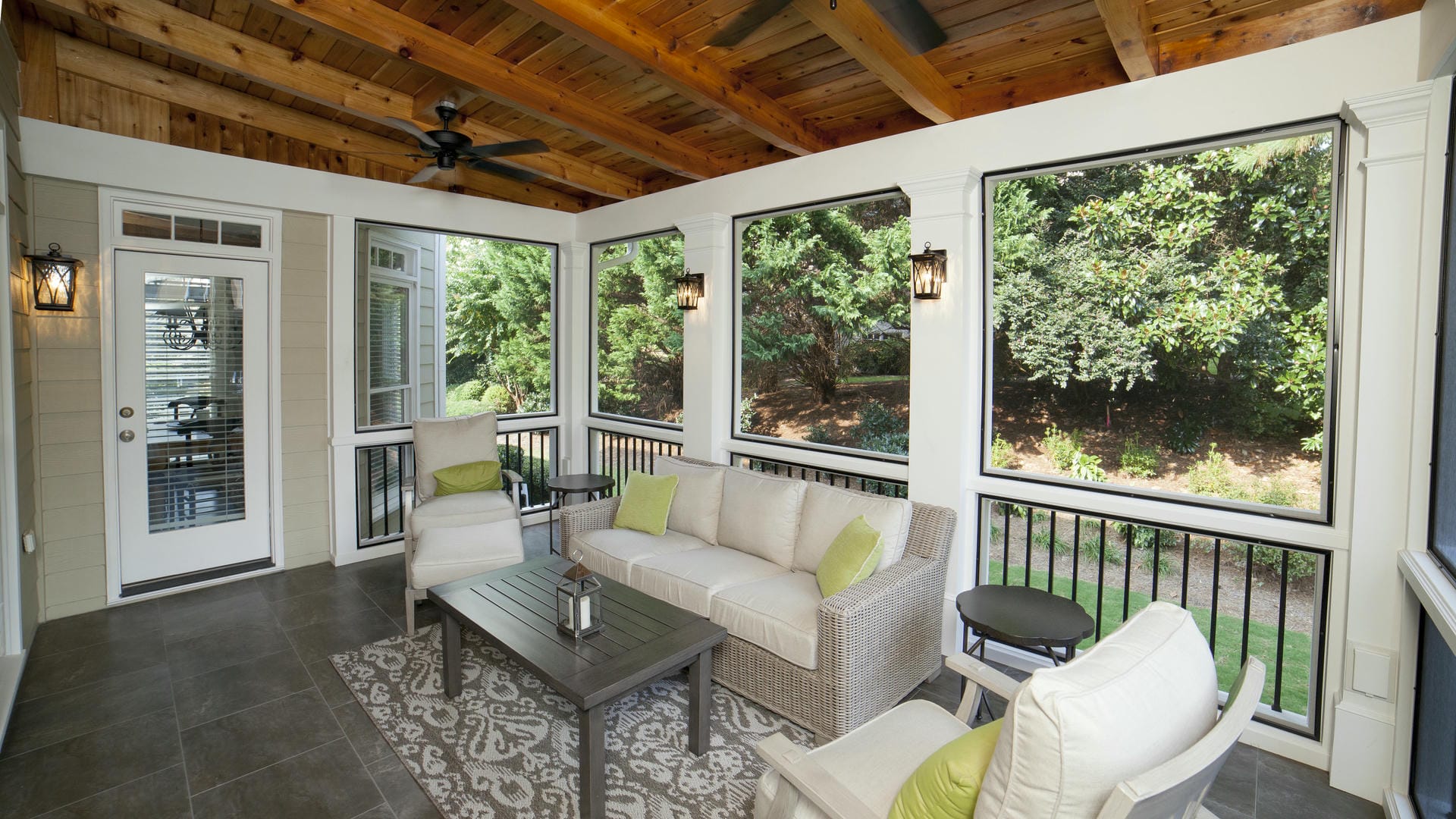 Screened porch interior with a cedar rafter ceiling, tile floor and cream wicker seating