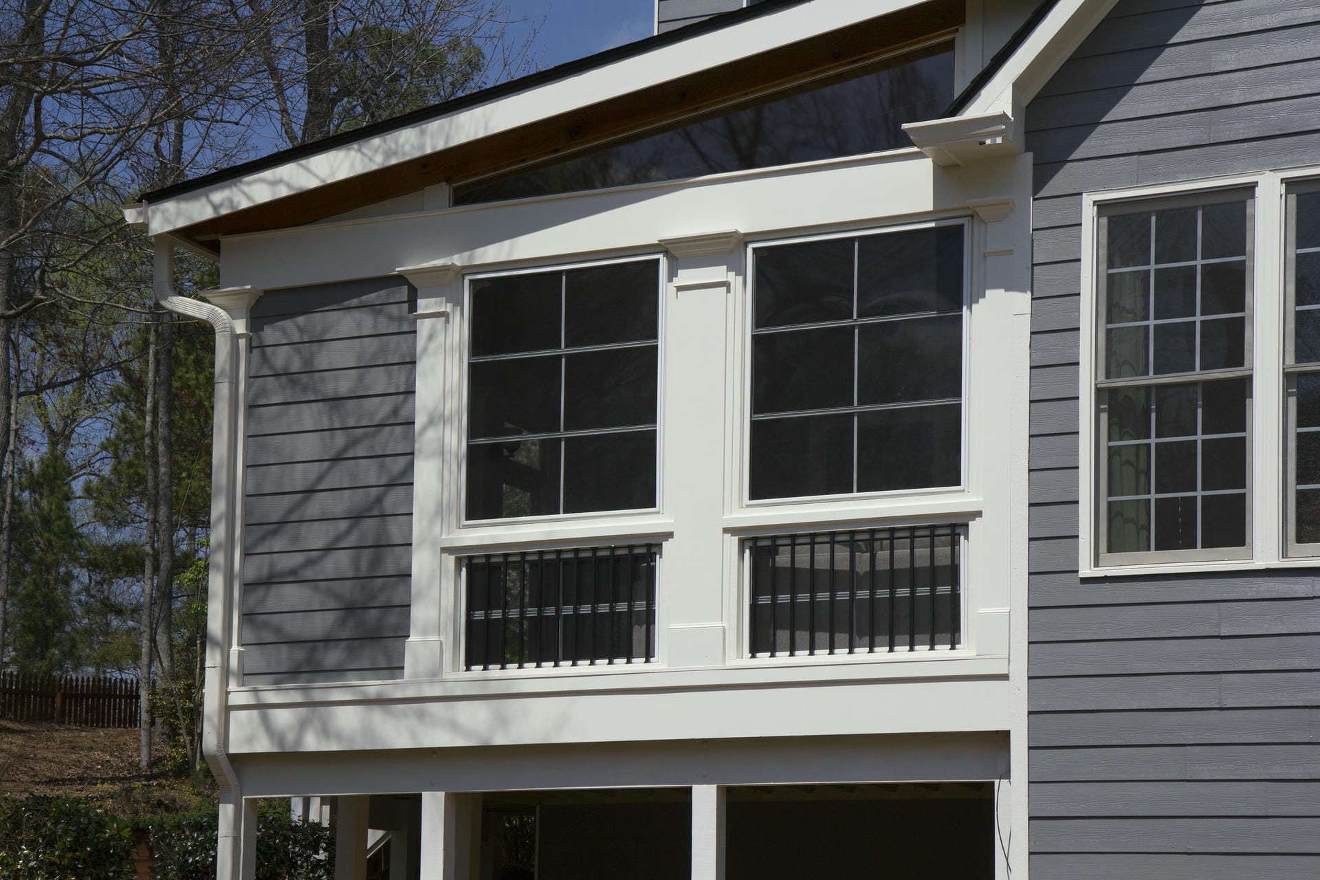 Shed porch roof with exposed rafter tails above a screened porch window wall