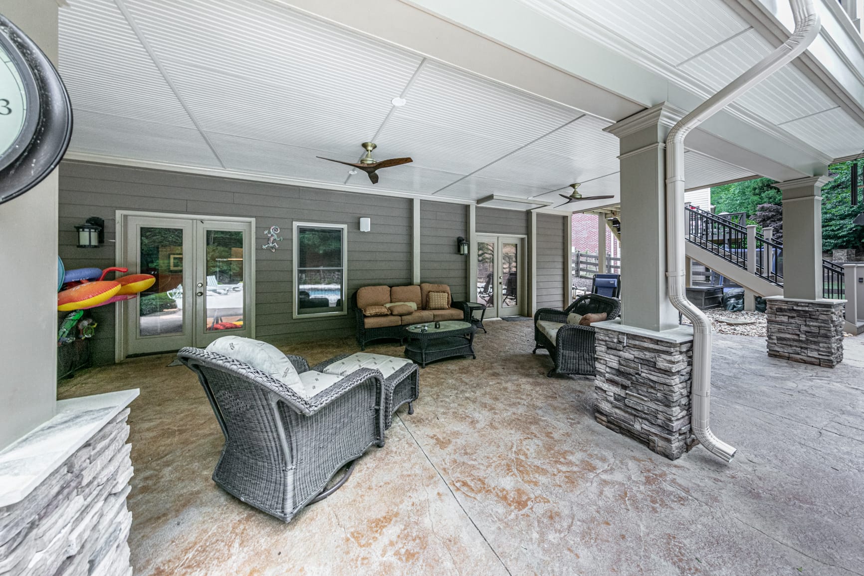 Finished space under a deck with stone column bases and a white plank ceiling