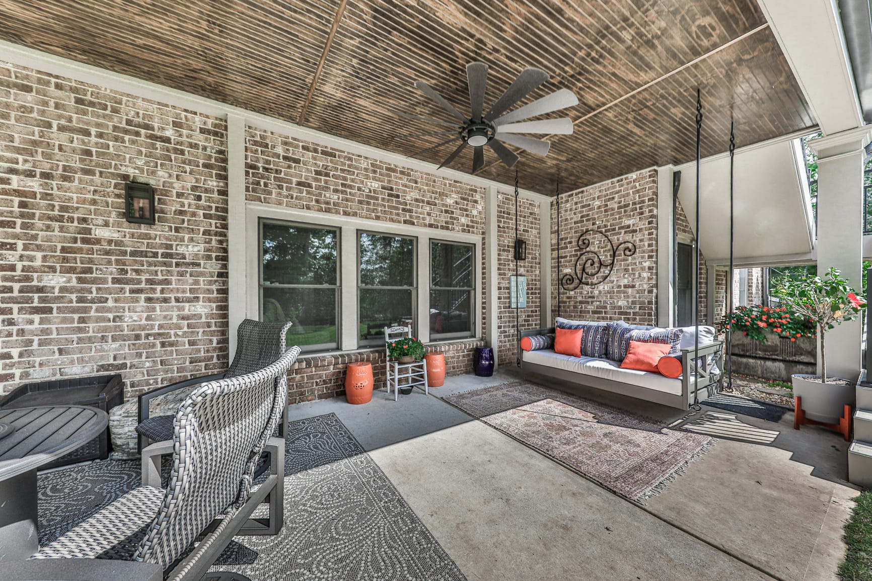 Under deck patio with a stained wood ceiling, ceiling fan and a hanging porch swing