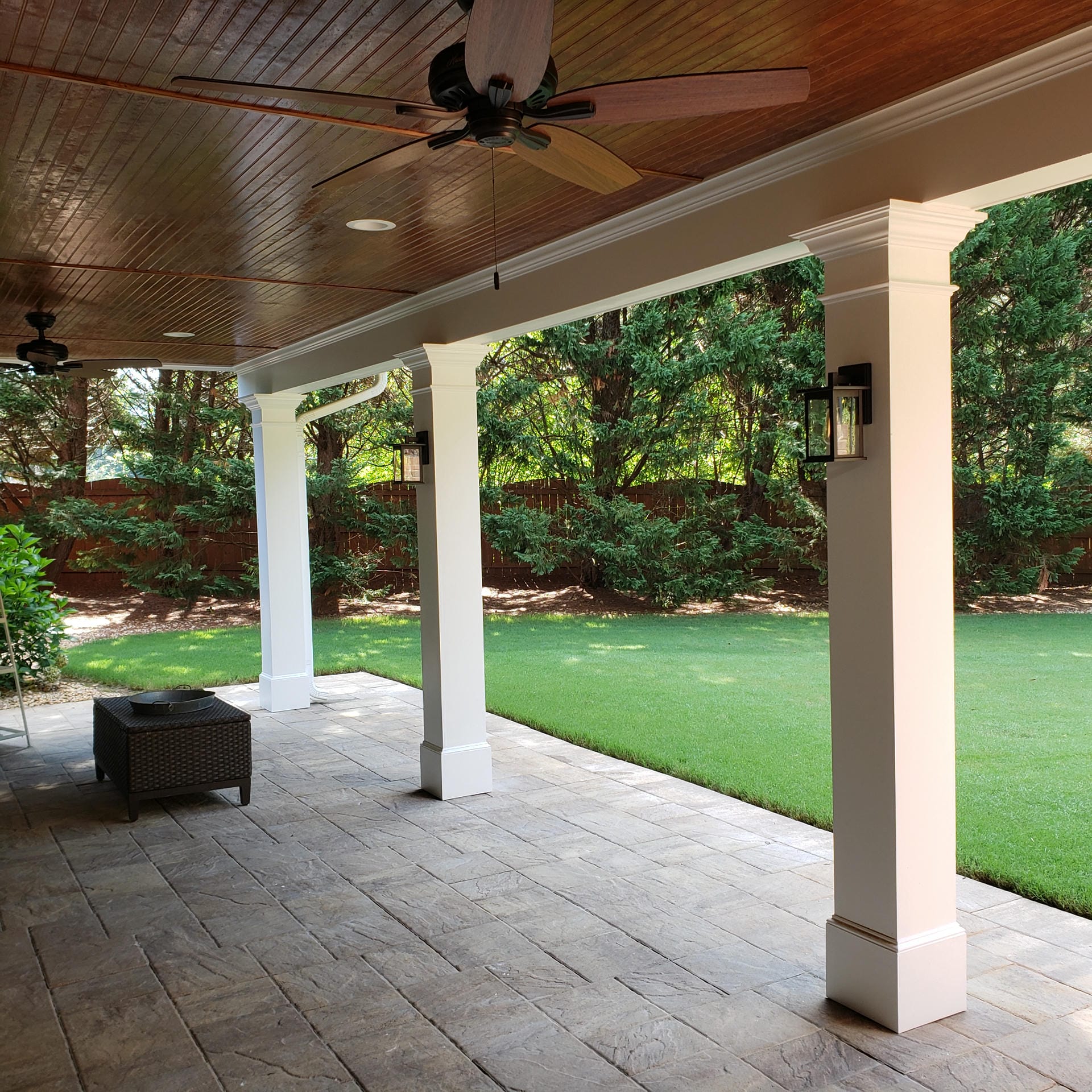 Stained wood ceiling under a deck with recessed lighting and a paver floor