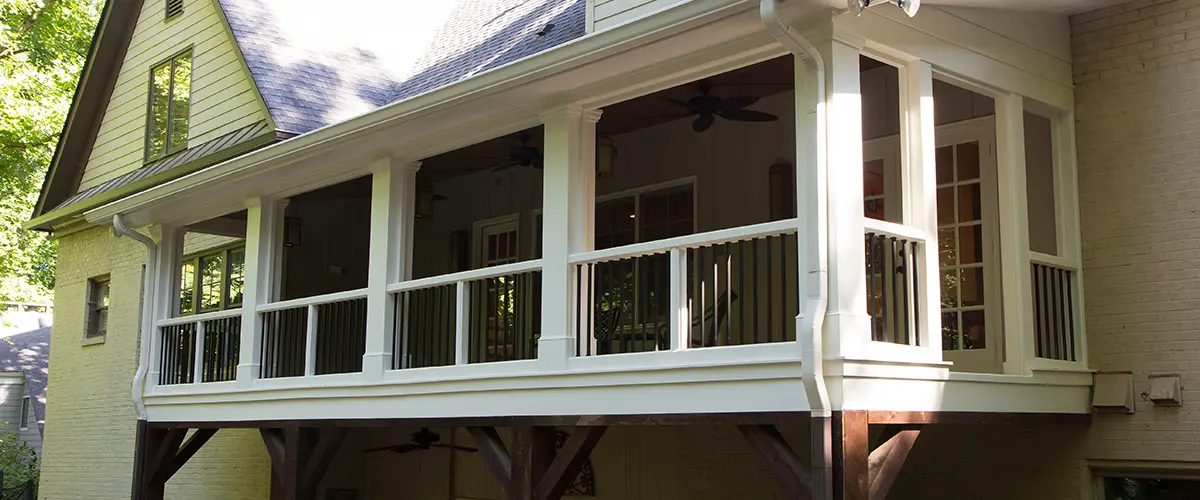 Covered back porch with white columns, black railings and elevated outdoor living space