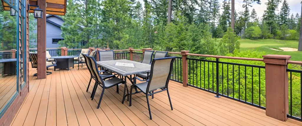 Outdoor deck with dining area, metal railing, and scenic wooded backyard views