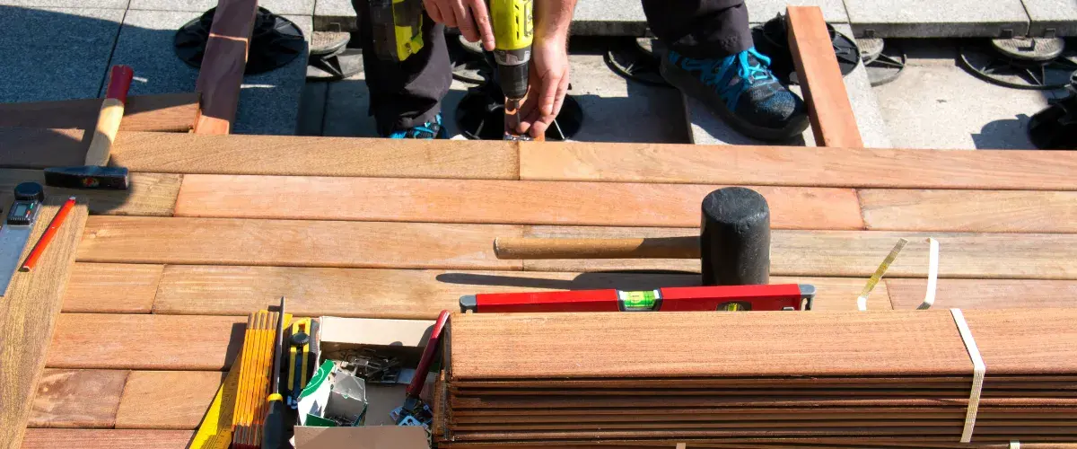 Professional deck installation with wood decking boards, power tools and framing in progress