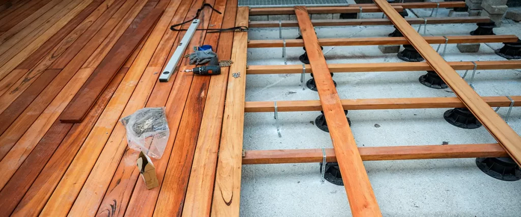 Wood deck installation in progress with framing, deck boards, and construction tools