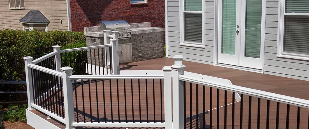 Composite backyard deck with black railing, built-in outdoor grill, and wide entertaining space