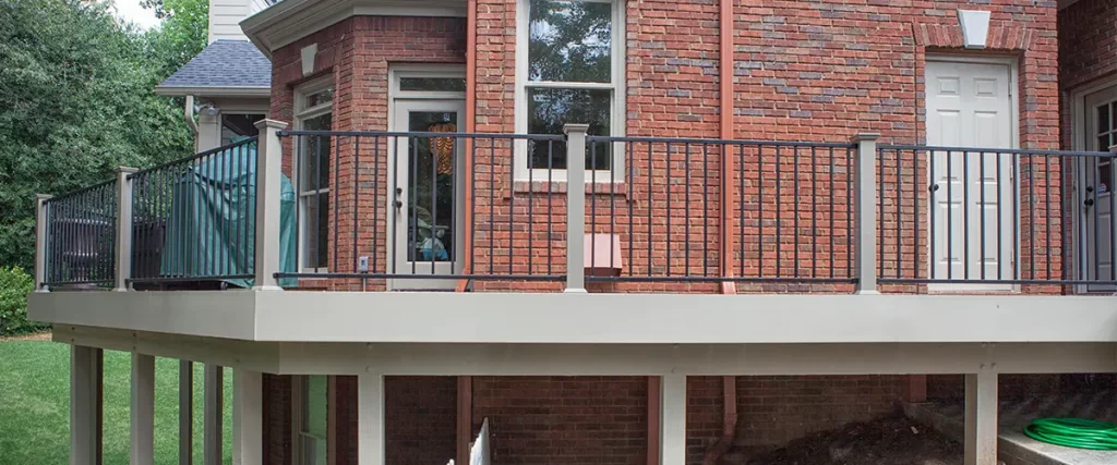 Elevated backyard deck with metal railing attached to a brick home