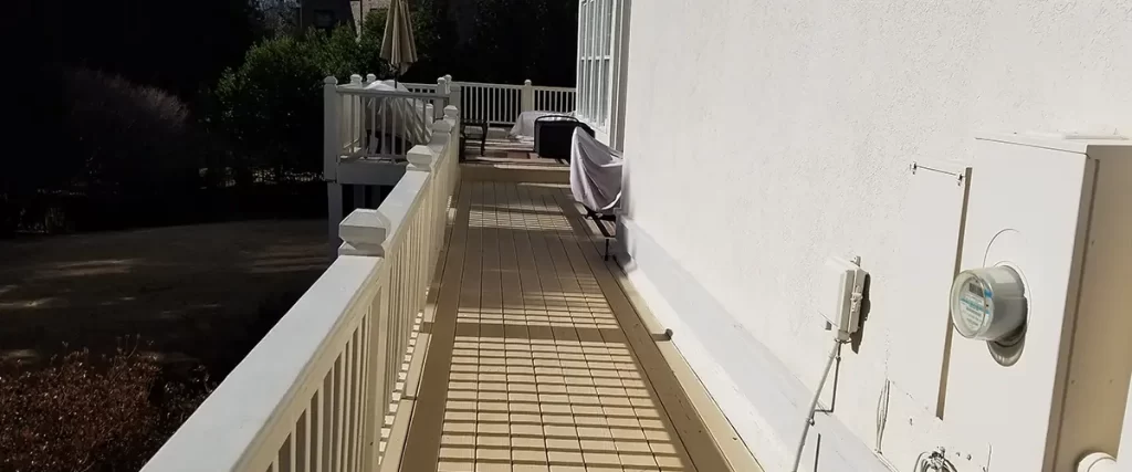 Elevated backyard deck with white railing and outdoor seating attached to a stucco home