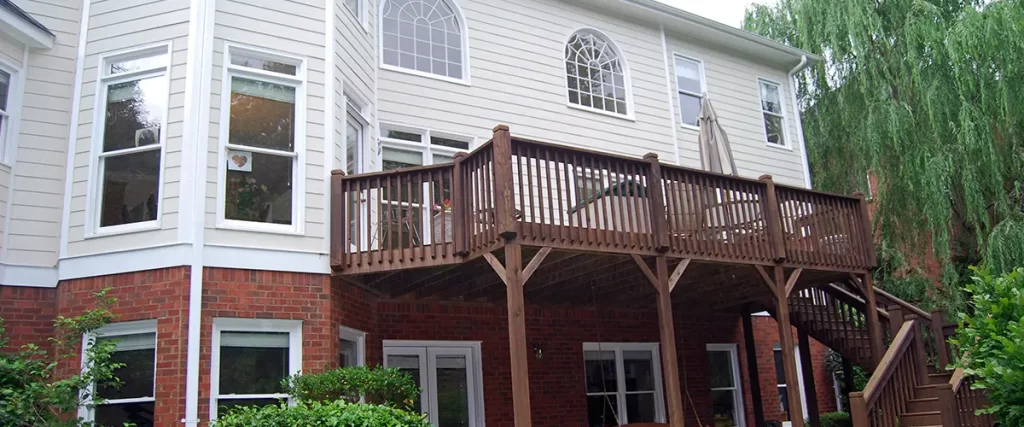 Elevated wood deck with stairs and railing overlooking a landscaped backyard