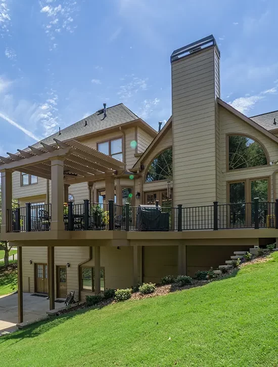 Large raised deck with pergola, outdoor seating and black railings on a two-story home.