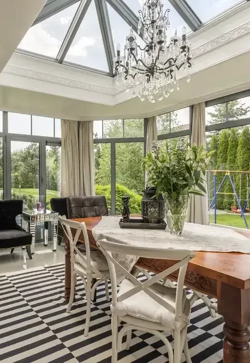 Luxury sunroom addition with glass ceiling, floor-to-ceiling windows and elegant dining area